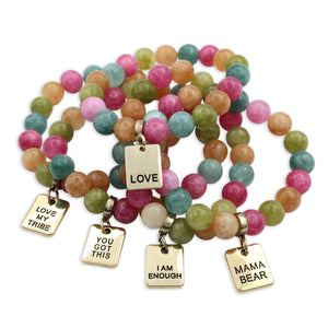 Set of colourful beaded bracelets with gold charms on a white background