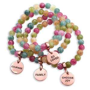 Multicolored beaded bracelets with rose gold charms on a white background