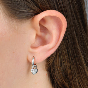 Silver heart earrings in ears