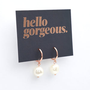 Rose gold earrings with pearl drops on a 'hello gorgeous' card.