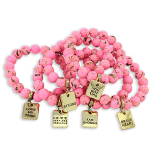Pink beaded bracelets with gold charms on a white background