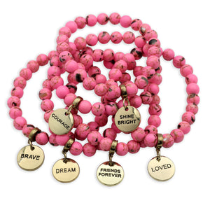 Pink beaded bracelets with gold charms on a white background