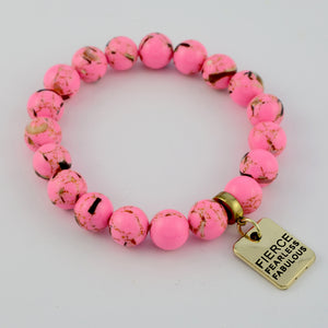 Pink beaded bracelet with a gold tag, reading Fierce Fearless Fabulous on a white background