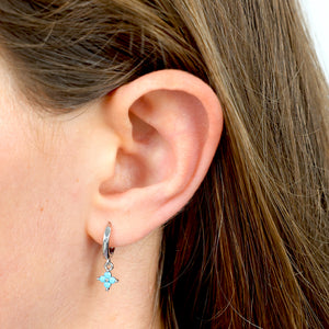 Close-up of an ear wearing a turquoise earring with a blurred background