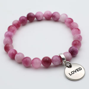 Pink beaded bracelet with a 'LOVED' charm on a white background