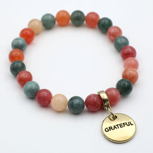 Multicolored beaded bracelet with a gold 'GRATEFUL' charm on a white background