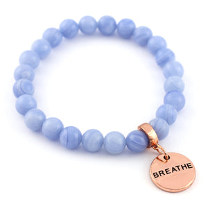 Blue beaded bracelet with a rose gold 'BREATHE' charm on a white background