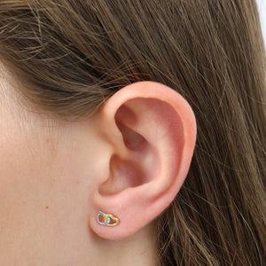 Close-up of an ear wearing a gold heart-shaped earring with hair partially obscuring the view.