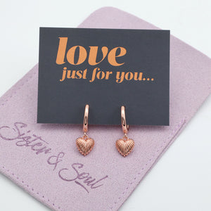 Rose gold heart-shaped earrings on a 'love just for you' card with a purple card holder.