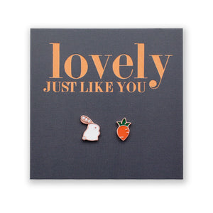 A pair of sterling silver stud earrings with one designed as a bunny and the other as a carrot, presented on a card with 'lovely just like you' printed in rose gold lettering.