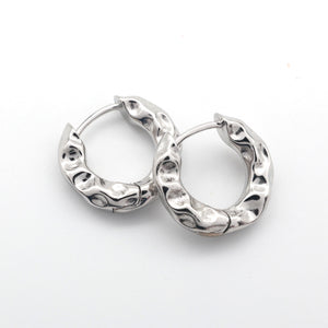 closed Silver Huggies hoop earrings on a white background