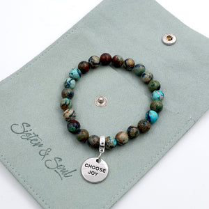 Beaded bracelet with 'Choose Joy' charm on a green card with 'Sister & Soul' branding.