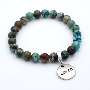 Beaded bracelet with a 'LOVED' charm on a white background