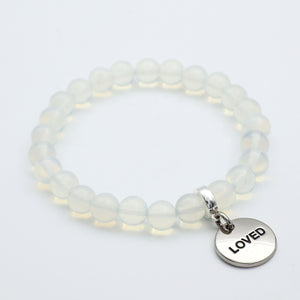 Beaded bracelet with a 'LOVED' charm on a light background