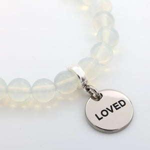 Bracelet with 'LOVED' charm on a light background