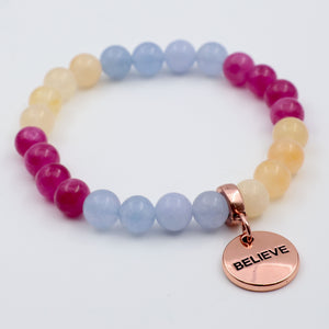 Multicolored beaded bracelet with a rose gold 'BELIEVE' charm on a white background