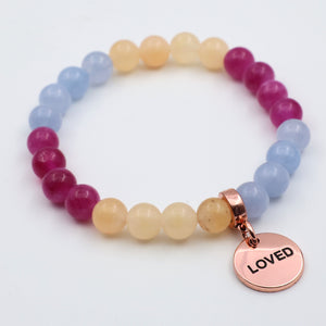 Multicolored beaded bracelet with a rose gold charm labeled 'LOVED' on a white background