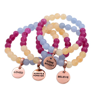 Set of beaded bracelets with rose gold charms on a white background