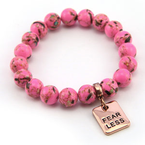 Pink beaded bracelet with a 'FEAR LESS' charm on a white background