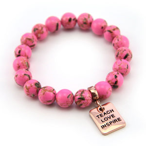 Pink beaded bracelet with a rose gold charm on a white background