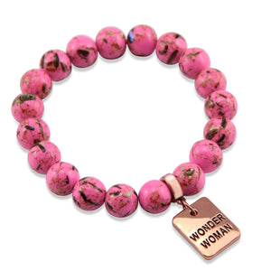 Pink beaded bracelet with a 'Wonder Woman' charm on a white background