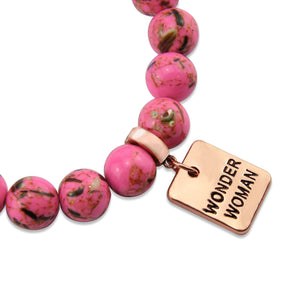 Pink beaded bracelet with a 'Wonder Woman' charm on a white background