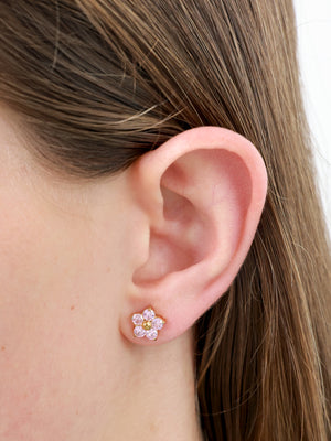 sparkly pink flower stud pictured on a girls ear.