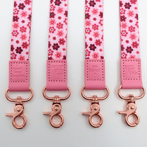 Four pink floral lanyards with rose gold clasp on a light gray background