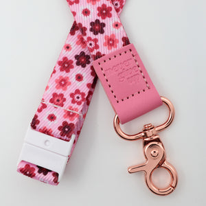 Floral lanyard with pink leather tag and rose gold clasp on a light gray background