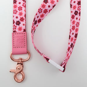 Floral patterned lanyard with pink strap and rose gold clasp on a light gray background