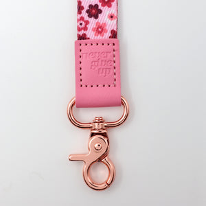 Pink floral ribbon with rose gold clasp on a light gray background