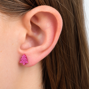 Pink glitter tree earrings in girls ear.