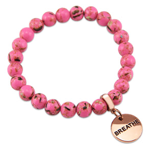 Pink beaded bracelet with a 'BREATHE' charm on a white background