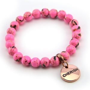 Pink beaded bracelet with a gold 'CHERISH' charm on a white background