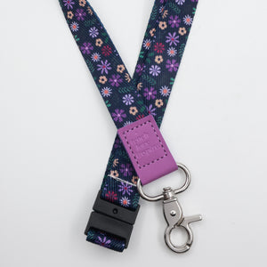 Teach Love Inspire embossed on a navy floral lanyard with purple trim and a lobster clasp.