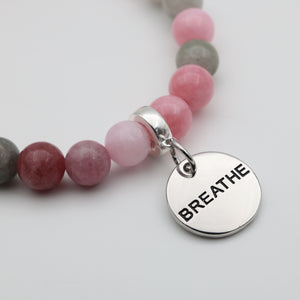 Necklace with pink and gray beads and a silver 'BREATHE' charm on a light background