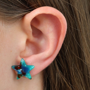 Close-up of an ear wearing a blue star-shaped earring.