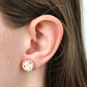 Close-up of an ear wearing a round earring with floral design.