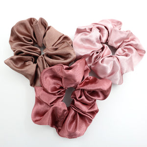 Three satin scrunchies in brown, pink, and dusty pink on a white background