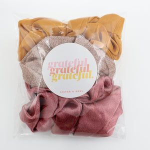Packaged scrunchies with 'grateful' label on a white background
