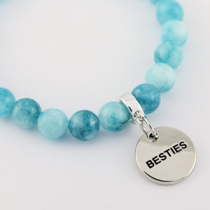 Turquoise beaded bracelet with a 'BESTIES' charm on a light blue background