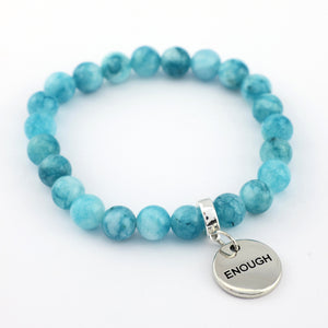 Turquoise beaded bracelet with a silver 'ENOUGH' charm on a white background