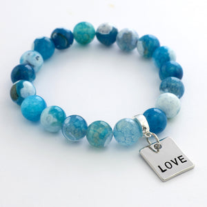 Blue beaded bracelet with a 'LOVE' charm on a white background