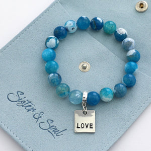 Blue beaded bracelet with 'LOVE' charm on a blue card with 'Sister & Soul' branding.