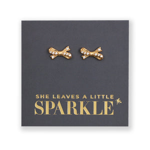 Gold bow shaped studs with clear gemstone features, on a card that says she leaves a little sparkle on a white background.