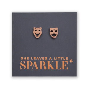 Earrings shaped like comedy and tragedy masks on a card with 'She Leaves a Little Sparkle' text.