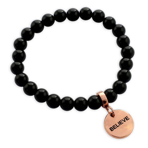Black beaded bracelet with a rose gold 'BELIEVE' charm on a white background
