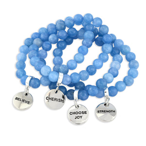 Set of blue beaded bracelets with motivational charms on a white background