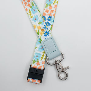 Be Kind embossed on a colourful floral lanyard with pale blue trim and a lobster clasp.