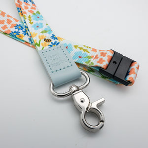 Teach Love Inspire embossed on a colourful floral lanyard with pale blue trim and a lobster clasp.